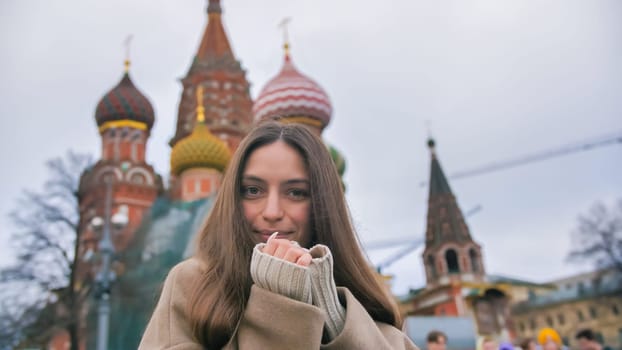 Happy smiling young woman portrait in Red Square, Moscow. A woman in the city warms her hands
