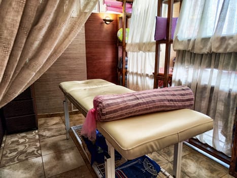 The well-equipped spa treatment area features a massage table with soft linens, surrounded by calming curtains and a soothing environment.