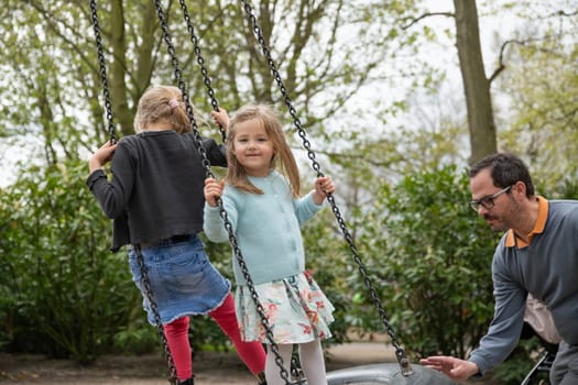 Father rolls daughter on a swing at a park
