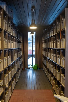 Numbered grey boxes filling narrow room with hanging lamp and watering can near window with winter view