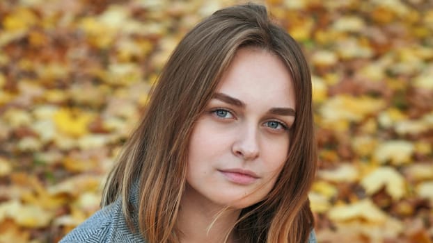 Portrait of a young and beautiful girl against a background of yellow leaves. Face close up