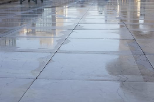 Water droplets glisten on a polished marble surface in the sunlight.