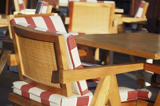 Wooden chairs with striped cushions surround a table at sunset.