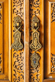 old wooden door with traditional Uzbek carved pattern and brass vintage handles in Tashkent in Uzbekistan