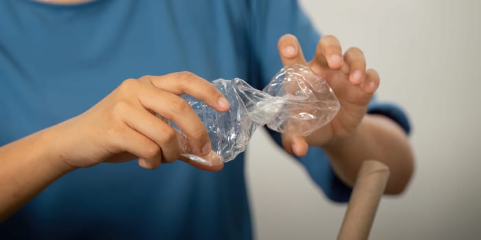 A child demonstrates recycling skills by crushing plastic bottles. This image highlights the importance of practical involvement in sustainability from a young age.