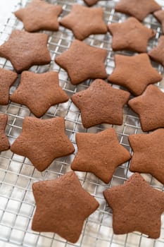 Wide-angle view of baked chocolate star cookies cooling on a wire rack.