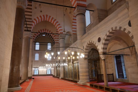 Interior view of a historic mosque showcasing arches and ornate lighting.