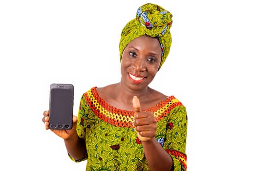 beautiful african adult woman dressed in loincloth and green scarf is happy showing thumbs up with her phone