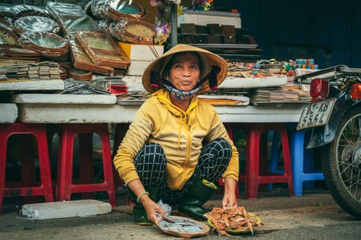 Vietnamese woman sells seafood at an Asian street market in old town in Hoi An in Vietnam in Asia. Hoi An, Vietnam - December 2, 2024