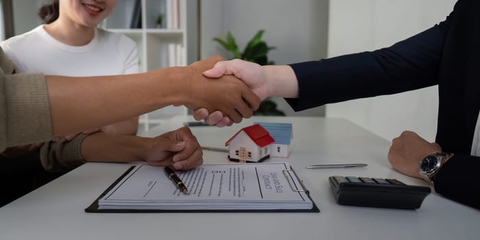 After finalizing their paperwork, the couple shakes hands with their agent, symbolizing the successful completion of their home-buying journey.
