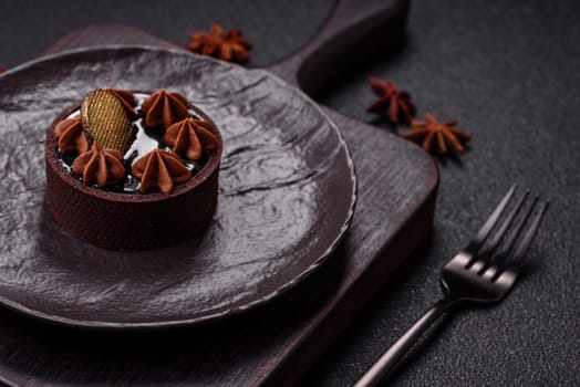 Sweet round tart with chocolate coating and nut filling on dark concrete background