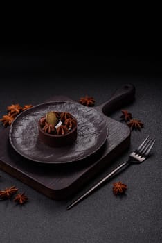Sweet round tart with chocolate coating and nut filling on dark concrete background