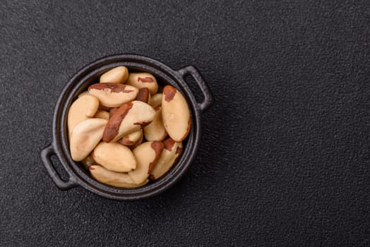 Brazil nut kernels in ceramic bowl on dark concrete background