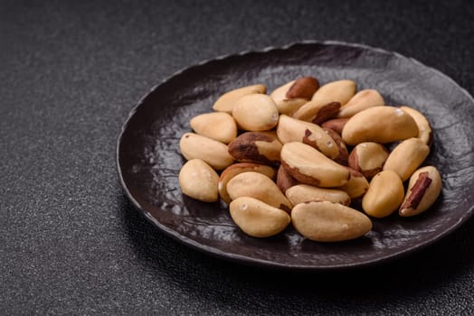 Brazil nut kernels in ceramic bowl on dark concrete background