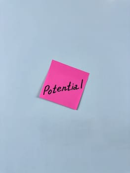 Sticky note with Potential written on it, affixed to white background. Image represents capability and opportunity, ideal for themes of potential and future growth