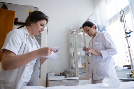 Two nurses in a hospital laboratory are carefully inspecting and preparing medications for patients and hospital use