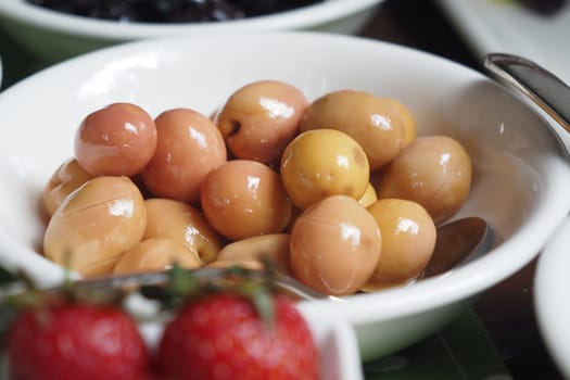 Plump olives sit in a bowl, ready for tasting during a meal.