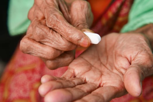 A senior individual gently applies cream to their hands, promoting skin health.
