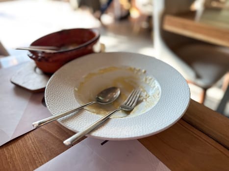 Empty plate with fork and spoon after meal in restaurant. Represents satisfaction, appetite, and the quiet moment after a delicious dining experience