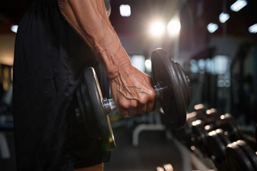 An elderly man focuses on strength training as he lifts a weight in a well equipped gym. The setting is bright, with a motivational atmosphere that encourages fitness.