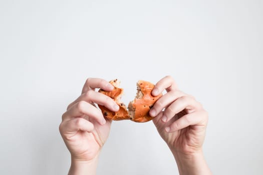 Hands breaking a bagel against a white background.