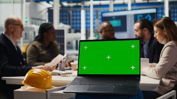 Shareholders in photovoltaics plant analyze market trends on green screen laptop to determine investment strategy. Managers look at data on chroma key notebook, expanding factory production, camera A