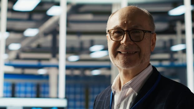 Smiling senior engineer in solar panels plant reading documentation to improve efficiency. Elderly man checking paperwork files in photovoltaics factory research and development department, camera B