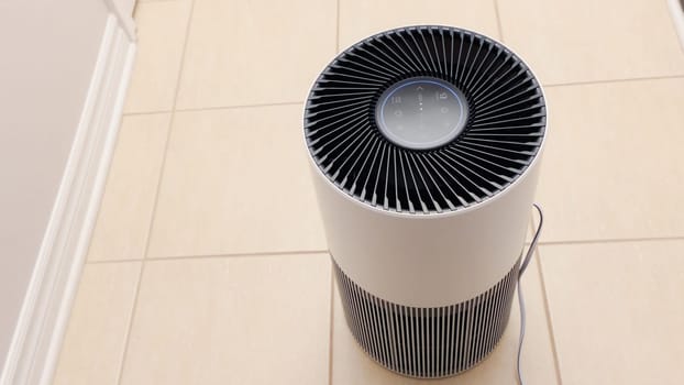 Close up view of Air Purifier with Black Fan. Black Round Electronic Device with Buttons and Bright Lights on White Background.
