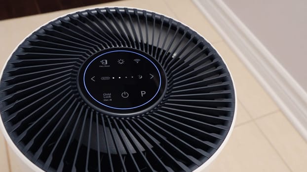 Close up view of Air Purifier with Black Fan. Black Round Electronic Device with Buttons and Bright Lights on White Background.
