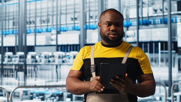 Industry 4.0 photovoltaics plant engineer overseeing using software on tablet to maximize solar cells power generation. African american man overseeing solar panels smart factory equipment, camera A