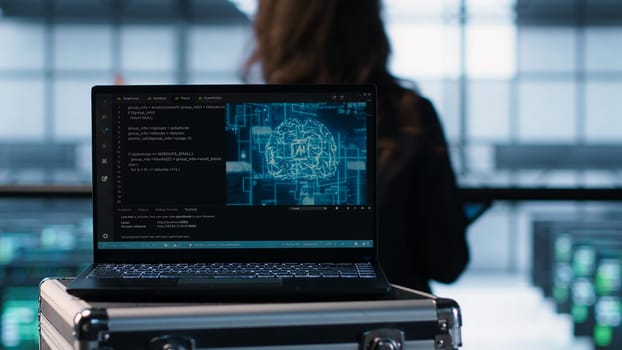 Laptop in front of data center engineers in background deploying artificial intelligence tools. AI coding on notebook screen next to technicians inspecting server clusters, camera A close up