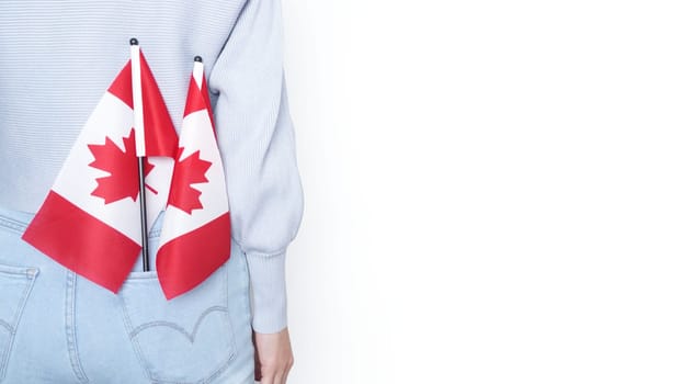 Miniature Canadian flags stands out of the back pocket of blue jeans