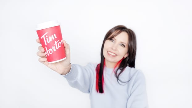 Cheerful Young Woman with Long Dark Hair Enjoying Tim Hortons Warm Cup of Coffee in Cozy Blue Sweater - Ottawa ON Canada -2024-10-28