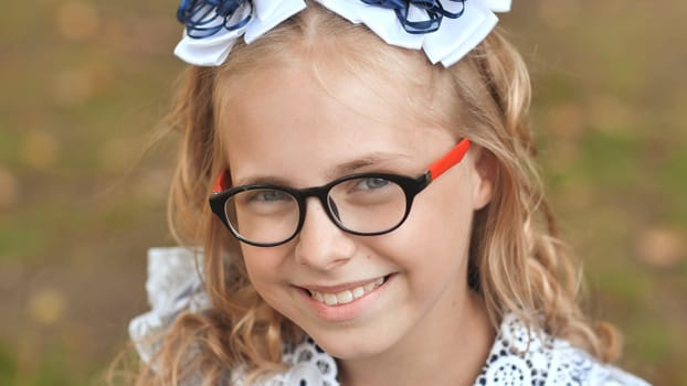 Portrait of a smiling 13 year old blonde girl pulling a bow over her head. Face close up