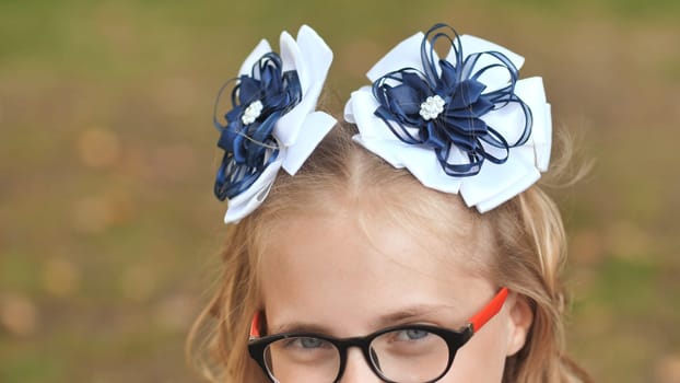 Schoolgirl posing in crisp white outfit, blue bows adorning hair, wearing glasses, preparing for academic journey