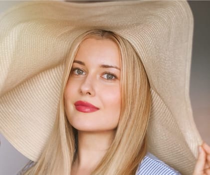 Woman, fashion and summer country charm, blonde beauty and elegance in wide brimmed beach hat. Feminine allure, timeless style and graceful glow. Smile, straw hat and blue striped blouse, natural lighting and effortless charm, fashion look idea