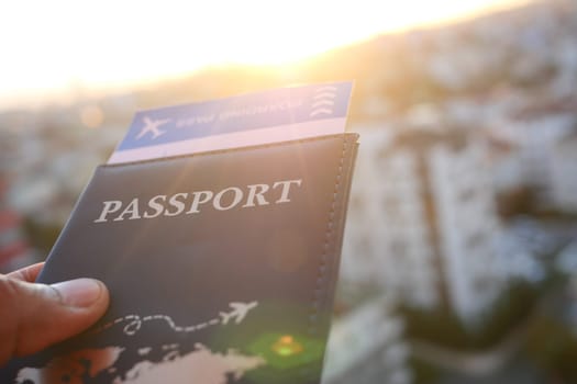 Holding a passport with a boarding pass against a sunset backdrop