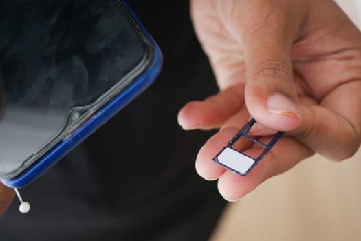 A hand holds a SIM card while preparing to insert it into a smartphone.