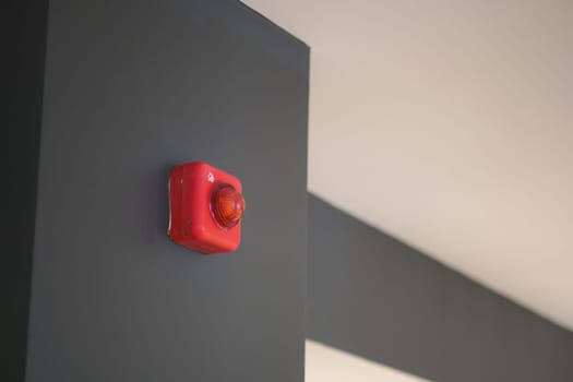 A bright red alarm light mounted on a dark wall enhances safety visuals indoors.