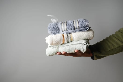 A person carefully holds three freshly folded towels in calming colors.