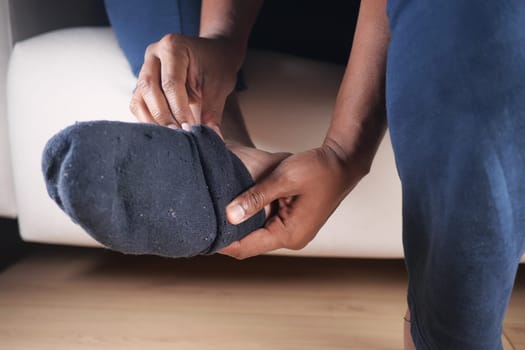 Individual adjusts a sock on their foot while sitting comfortably at home.