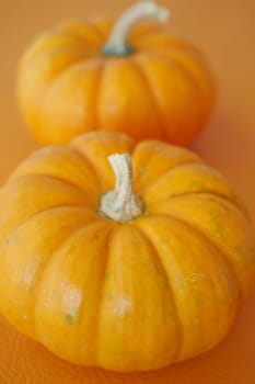 Bright orange pumpkins rest on an orange base, reflecting autumn hues.