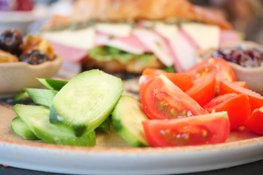 Fresh vegetables and a sandwich are artfully arranged for lunch.