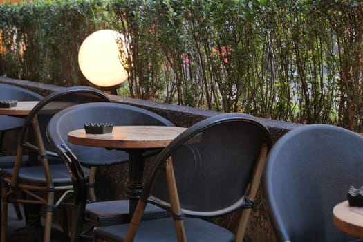 Several chairs and tables are arranged neatly outside a cafe at dusk.
