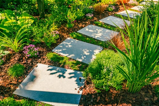Detail of garden path with stone slabs with bark mulch and native plants. Landscaping and gardening concept.