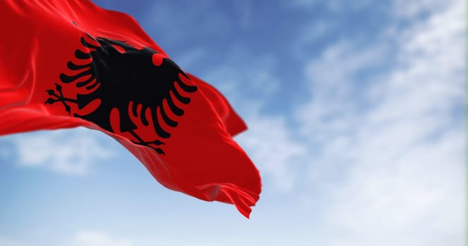 Albanian national flag waving in the wind on a clear day. Red flag with black two-headed eagle. 3d illustration render. Selective focus. Fluttering fabric