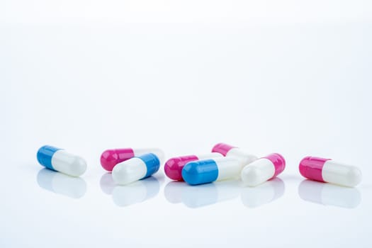 Blue and pink capsule pills spread on white background, showcasing pharmaceutical products, healthcare concepts, and the role of prescription medicine in advancing treatment and patient well-being.