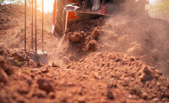Construction tractor with specialized dozer blade pushing and grading soil at excavation site. Heavy machinery transforming raw land into prepared foundation for upcoming building development project.