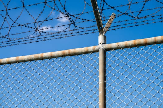 Barbed wire fence symbolizing border control, geopolitical tensions, and restricted freedoms in modern society. Barbed wire border security fence. Barrier border. Boundary security wall. Private area.