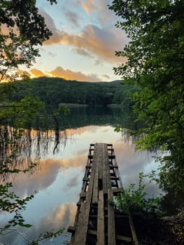Bridge to the forest lake at sunset